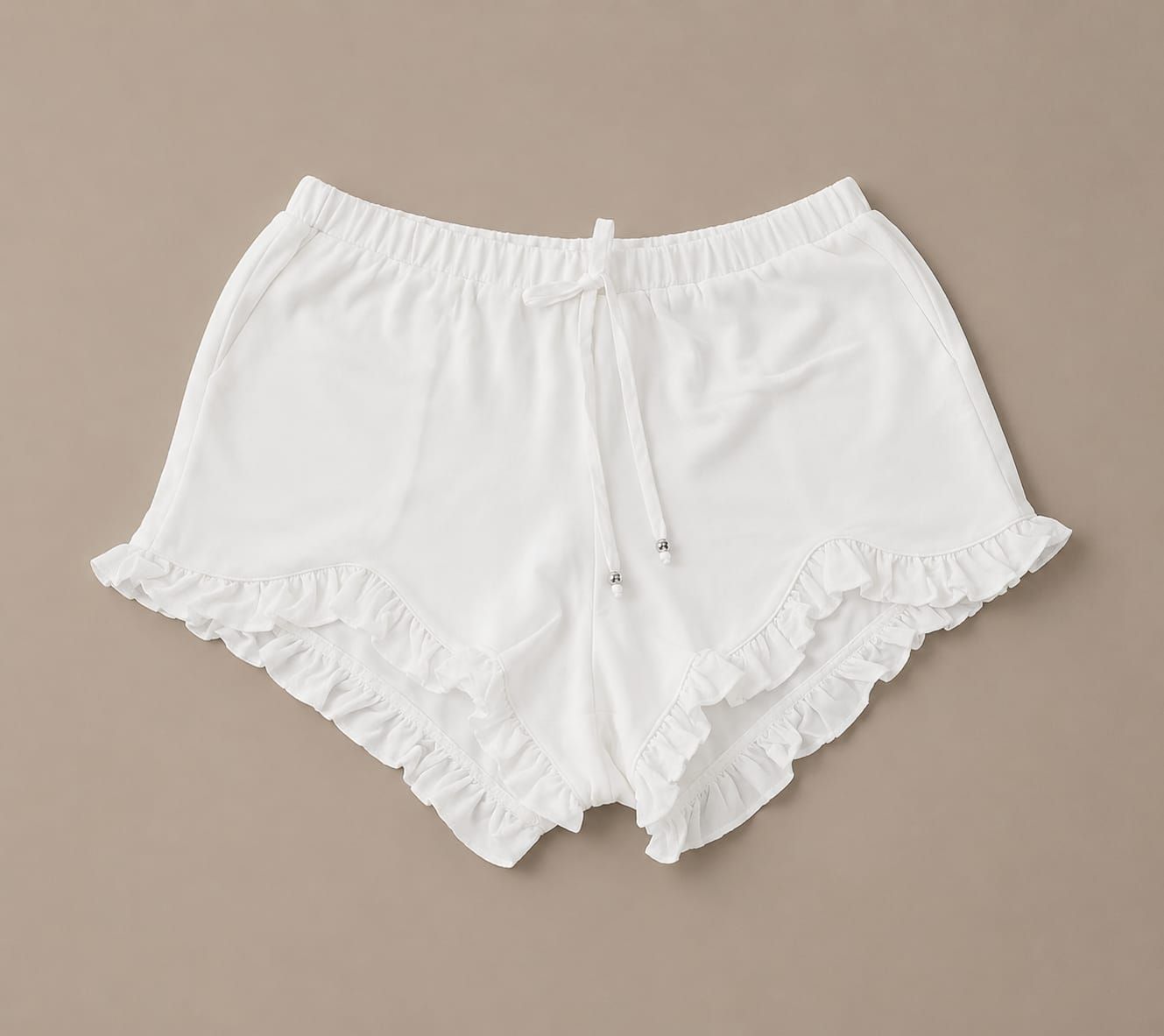 Persona vestida con blusa blanca y pantalones cortos, de pie en un paisaje desértico junto a grandes vasijas de barro.