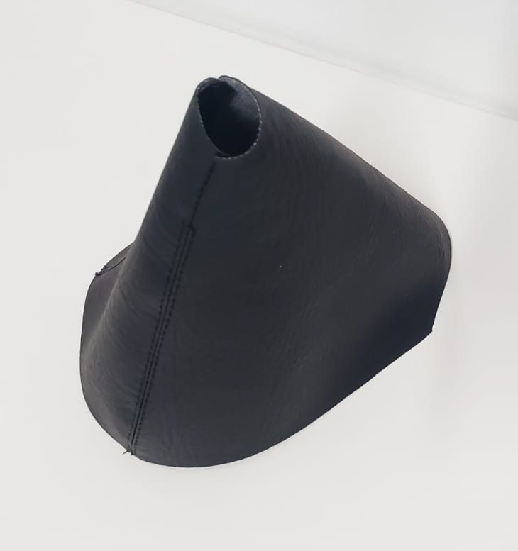 Artesanía negra en forma de cono con costuras cosidas sobre un fondo blanco.