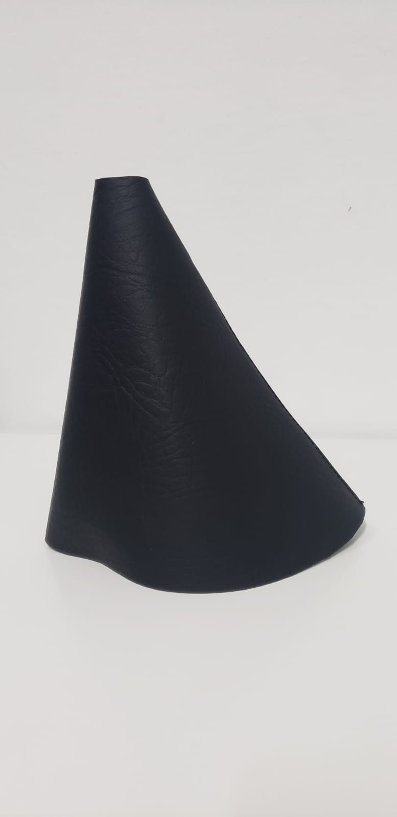 Objeto negro en forma de cono sobre un fondo claro.