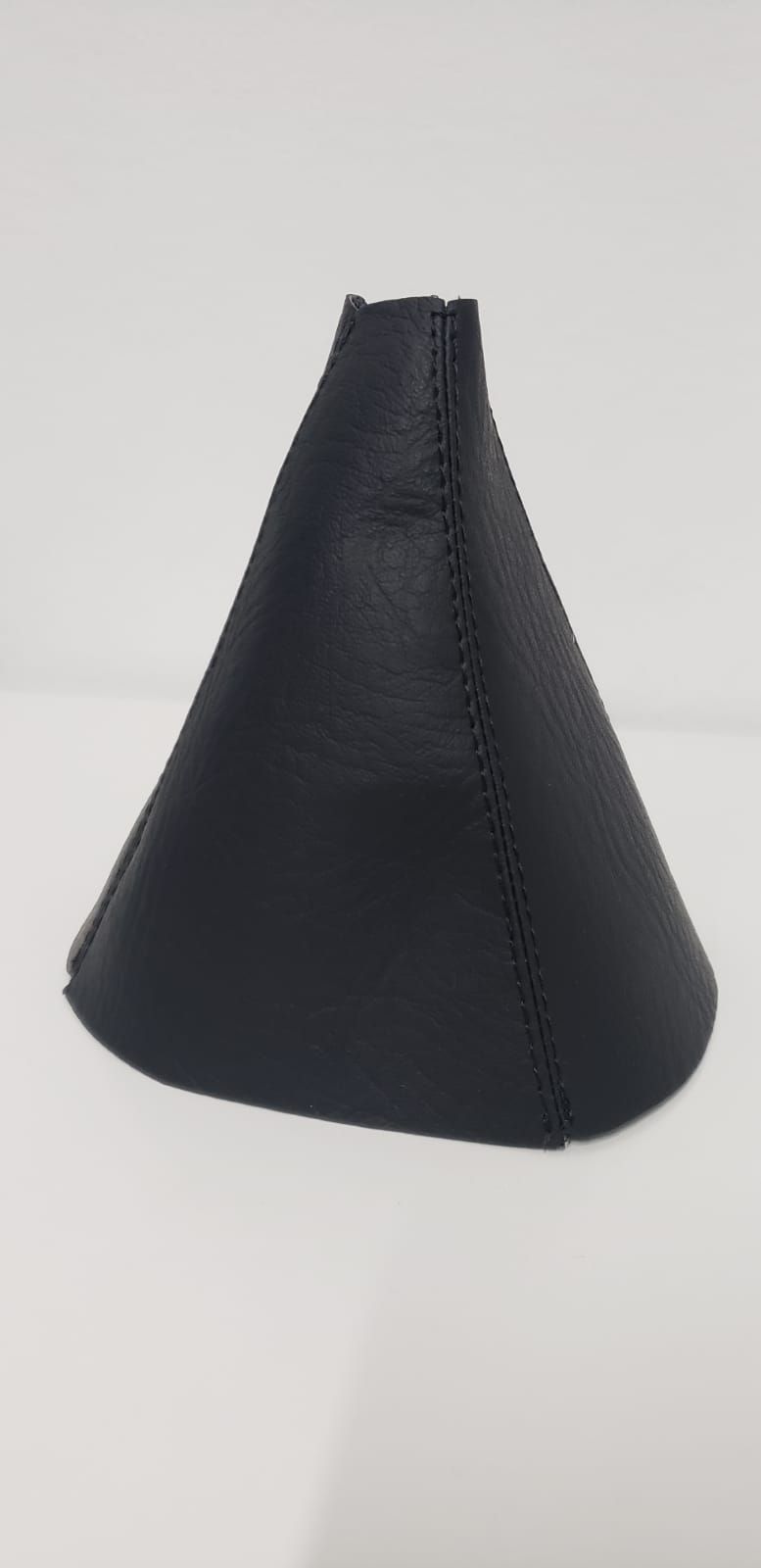 Estuche cónico de piel negra con costura cosida sobre fondo claro.
