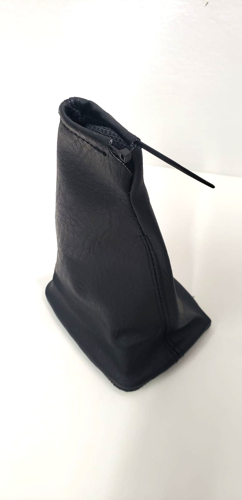 Bolsa negra con cordón, colocada en posición vertical sobre un fondo liso y claro.