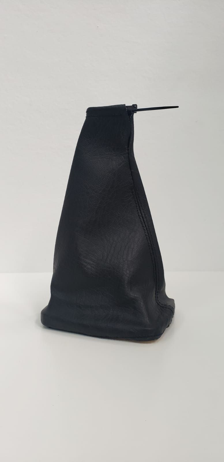 Bolsa negra con cordón, colocada en posición vertical sobre un fondo liso y claro.