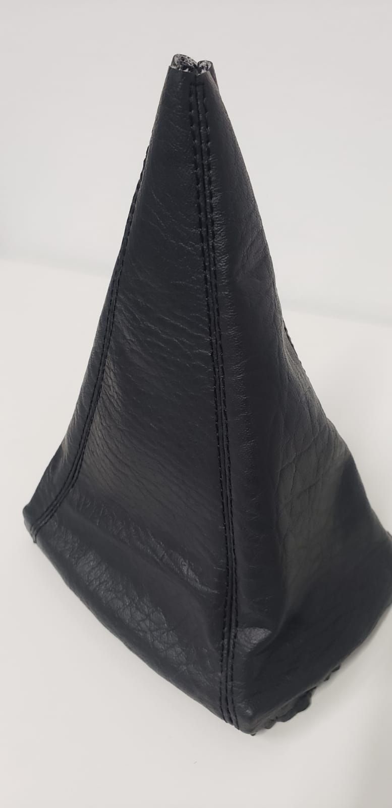 Palanca de cambios manual del coche con funda de cuero negro y pomo en la consola central.