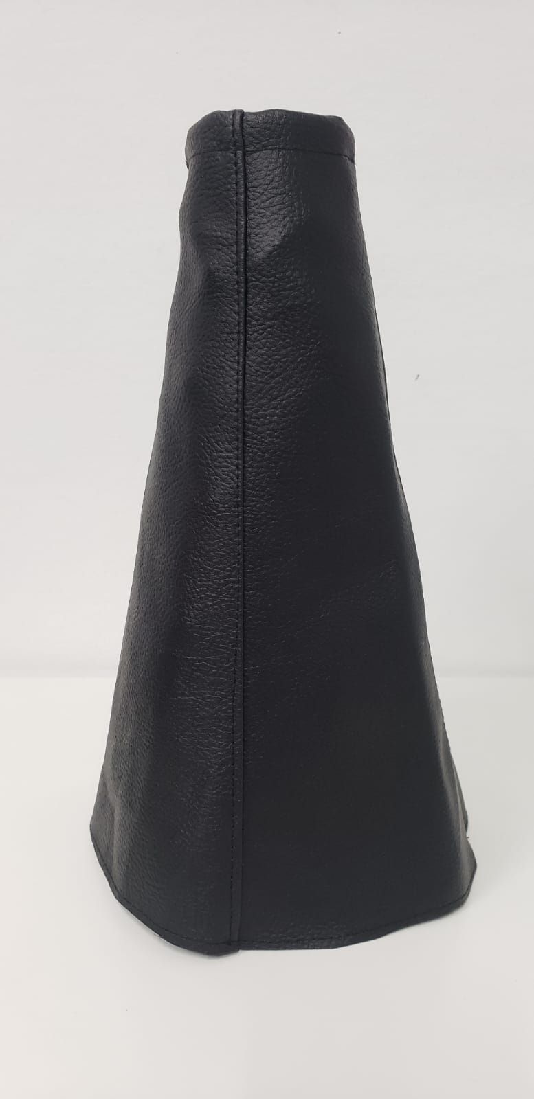 Objeto de cuero negro en forma de cono sobre un fondo blanco liso.