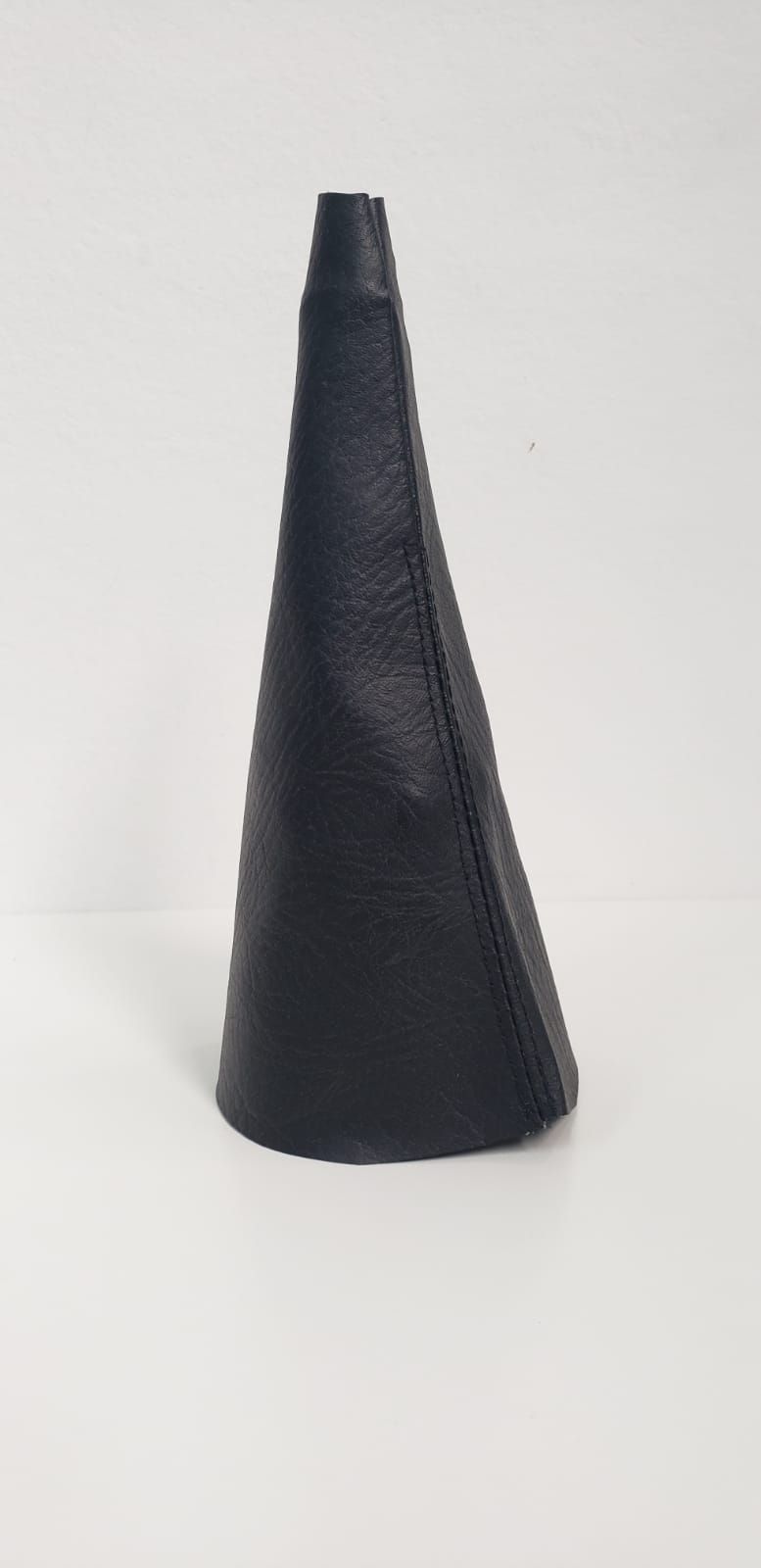 Objeto negro con forma de cono ahusado sobre un fondo blanco.