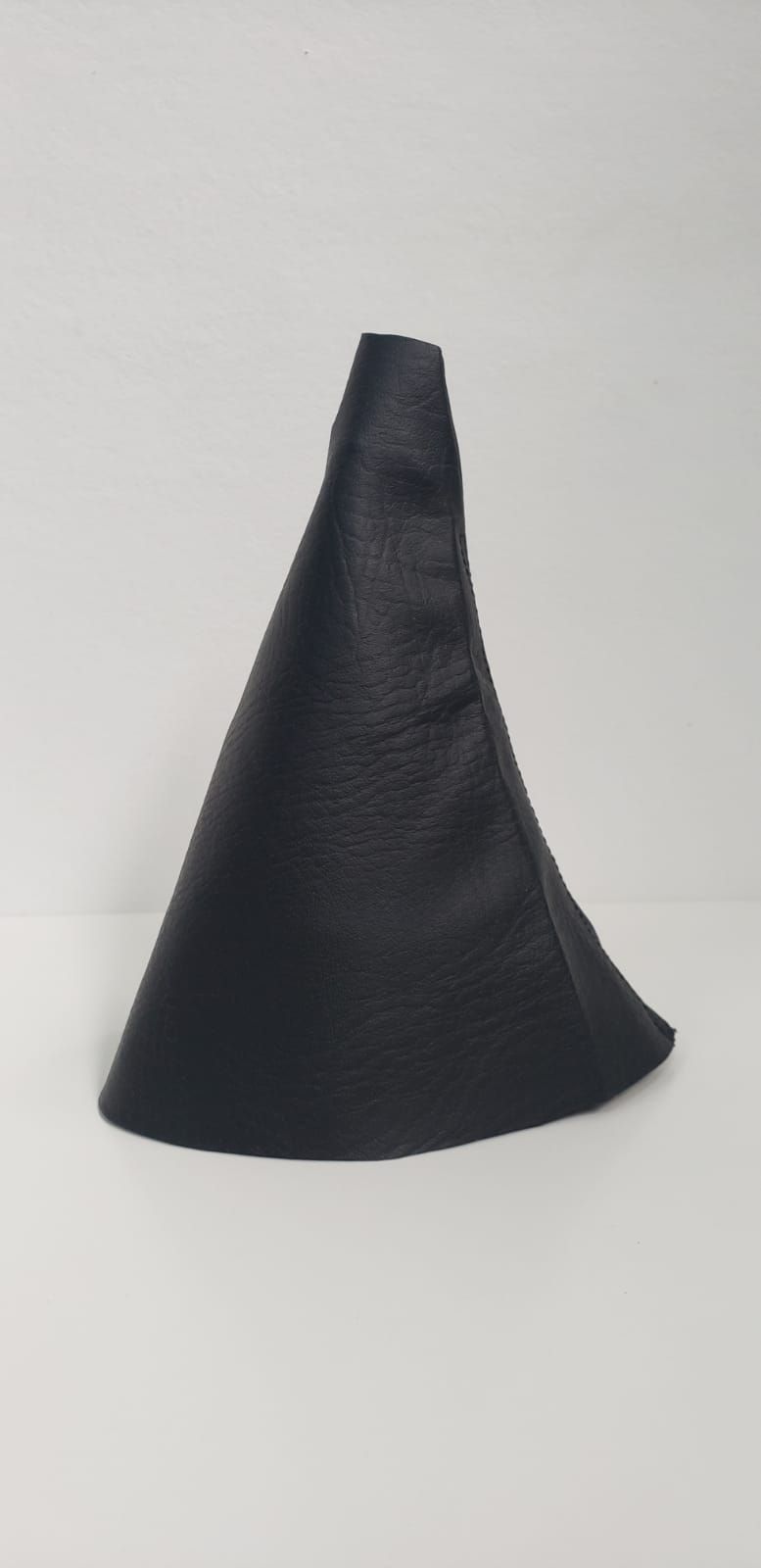 Cubierta de tela negra en forma de cono sobre un fondo liso claro.