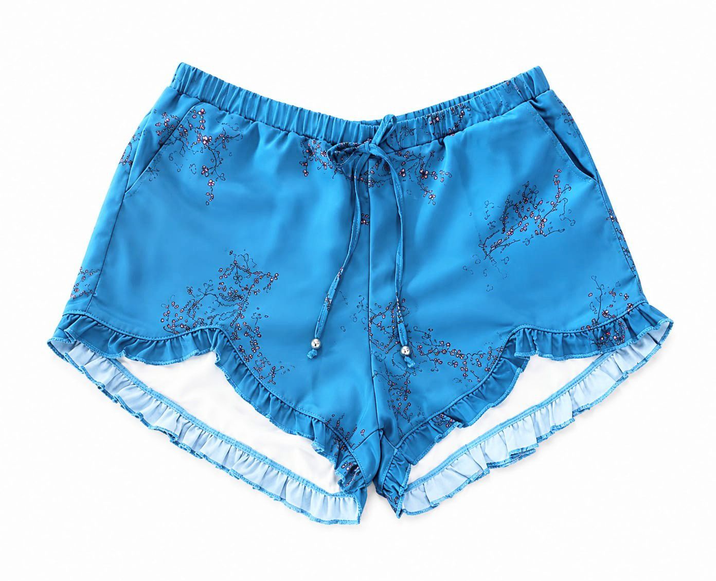 Persona de pie en aguas poco profundas, vestida con una blusa blanca y pantalones cortos azules con volantes.