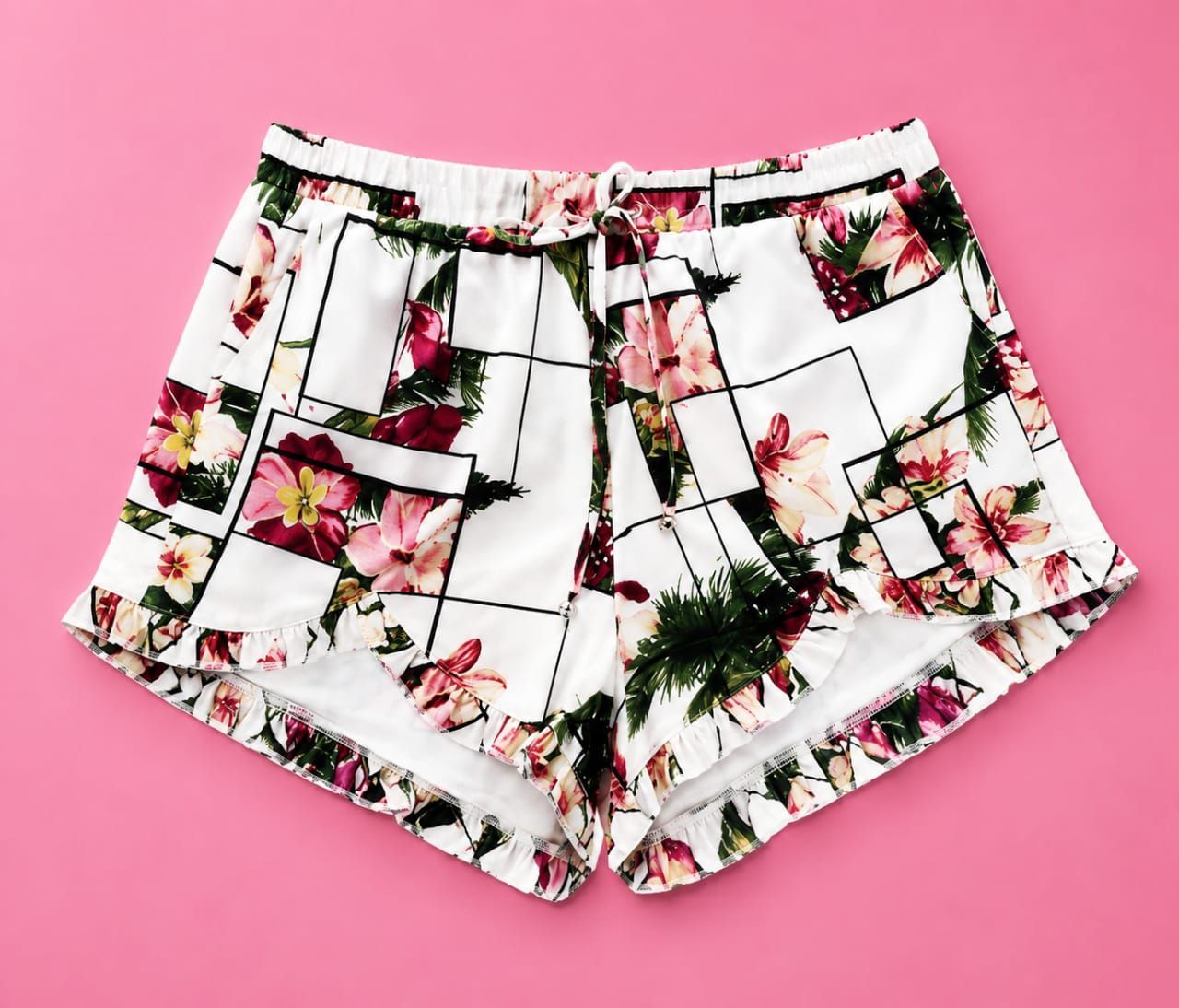 Mujer de pie sobre una roca junto a aguas verdes, con un top blanco sin tirantes, falda floral y sandalias.