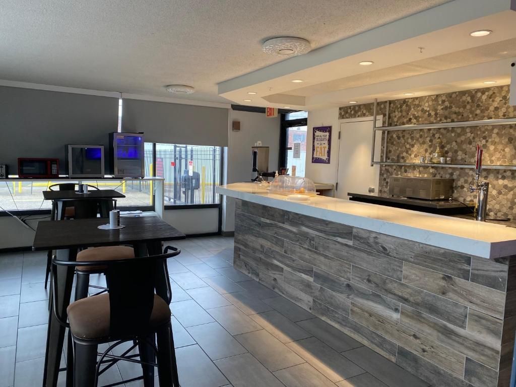 Interior view of a bar with a wooden counter, tables, stools, and large windows.
