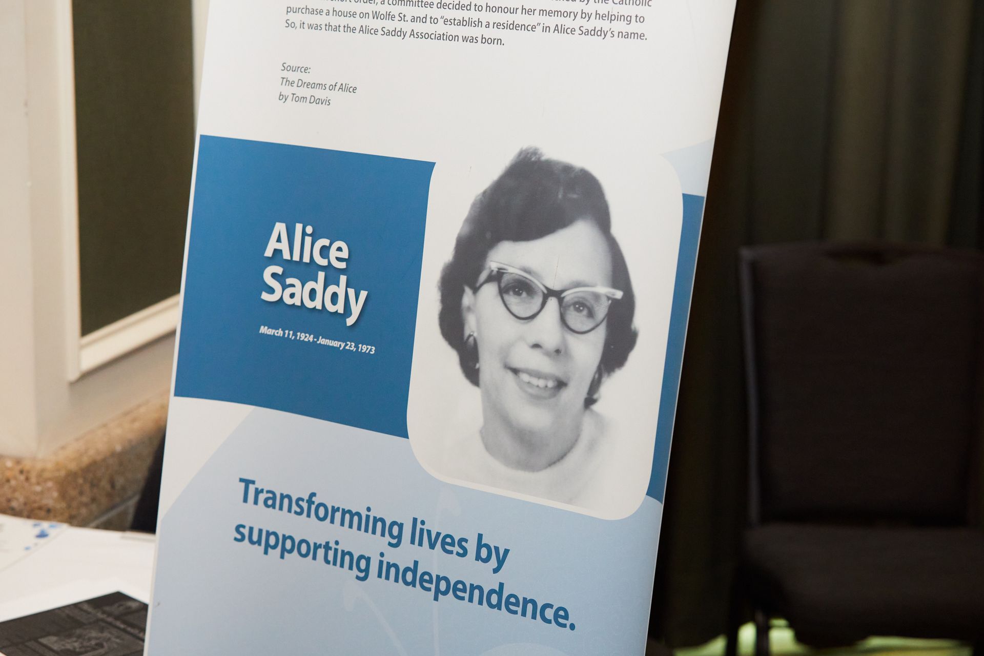 A poster for alice saddy is sitting on a table.