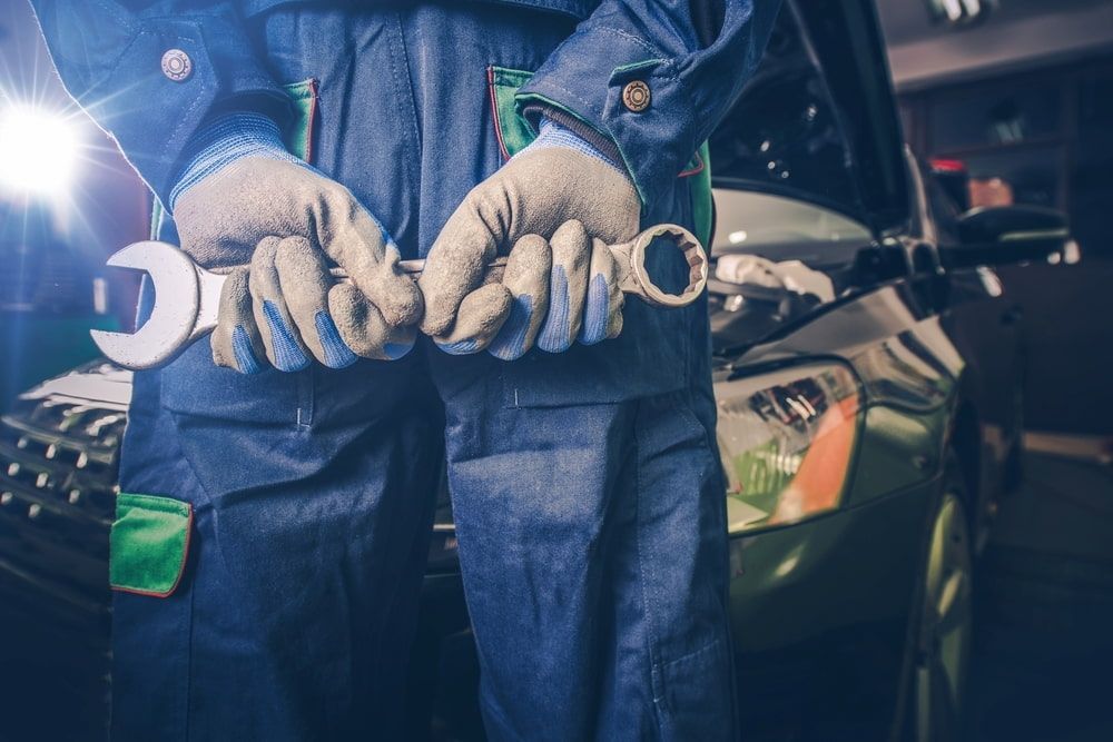 A Mechanic Is Holding A Wrench In Front Of A Car — A & D Automotive Technicians in Mackay, QLD