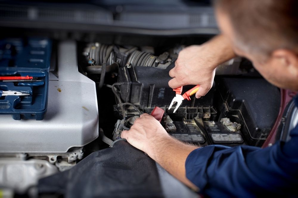 A Man Is Working On A Car Engine With Pliers — A & D Automotive Technicians in Mackay, QLD
