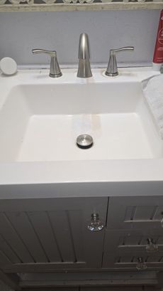 Bathroom vanity with white sink, chrome faucet, and gray cabinet doors below