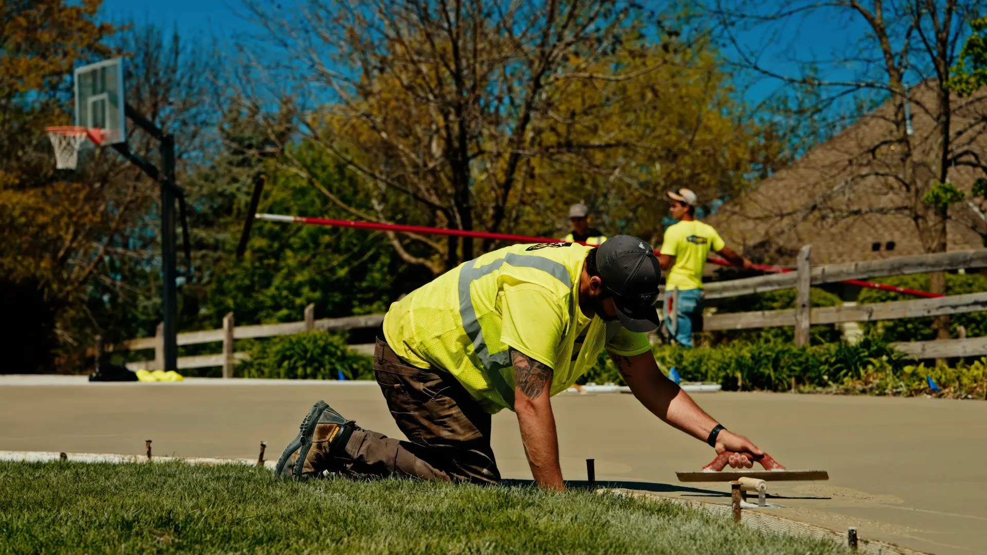 Road crew operating an asphalt paver beside a dump truck during a paving project.