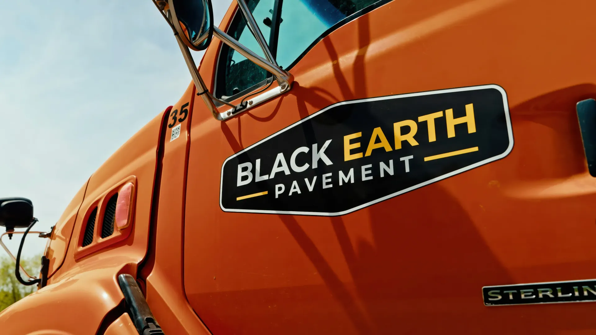 Orange heavy truck door with Black Earth Pavement logo and Sterling badge