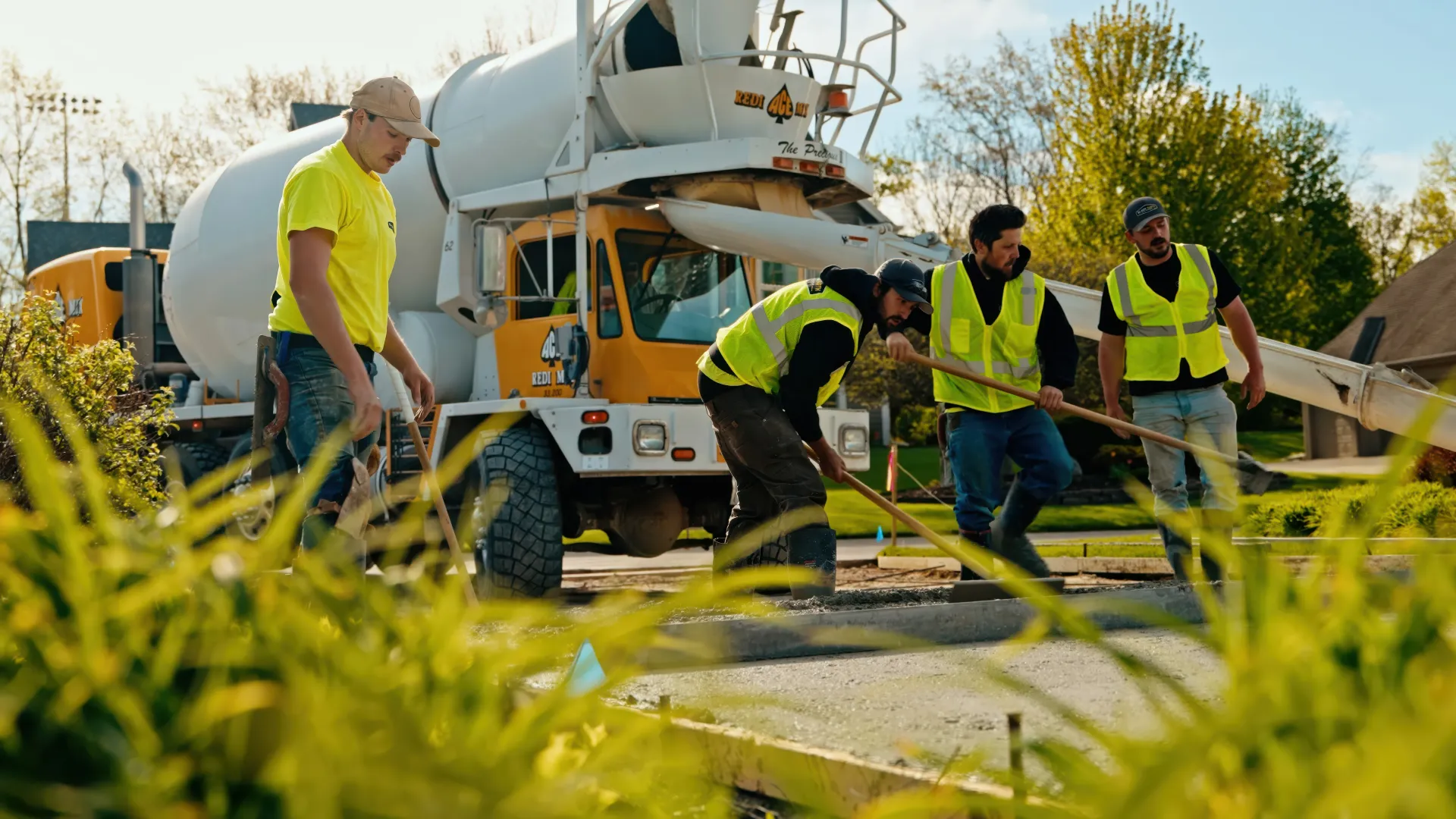 Workers in neon vests operating a concrete mixer at a construction site