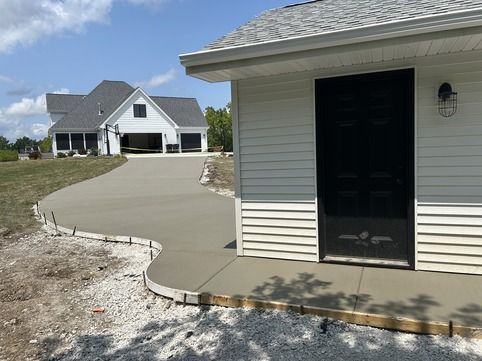 Freshly poured concrete walkway and patio around a residential garage