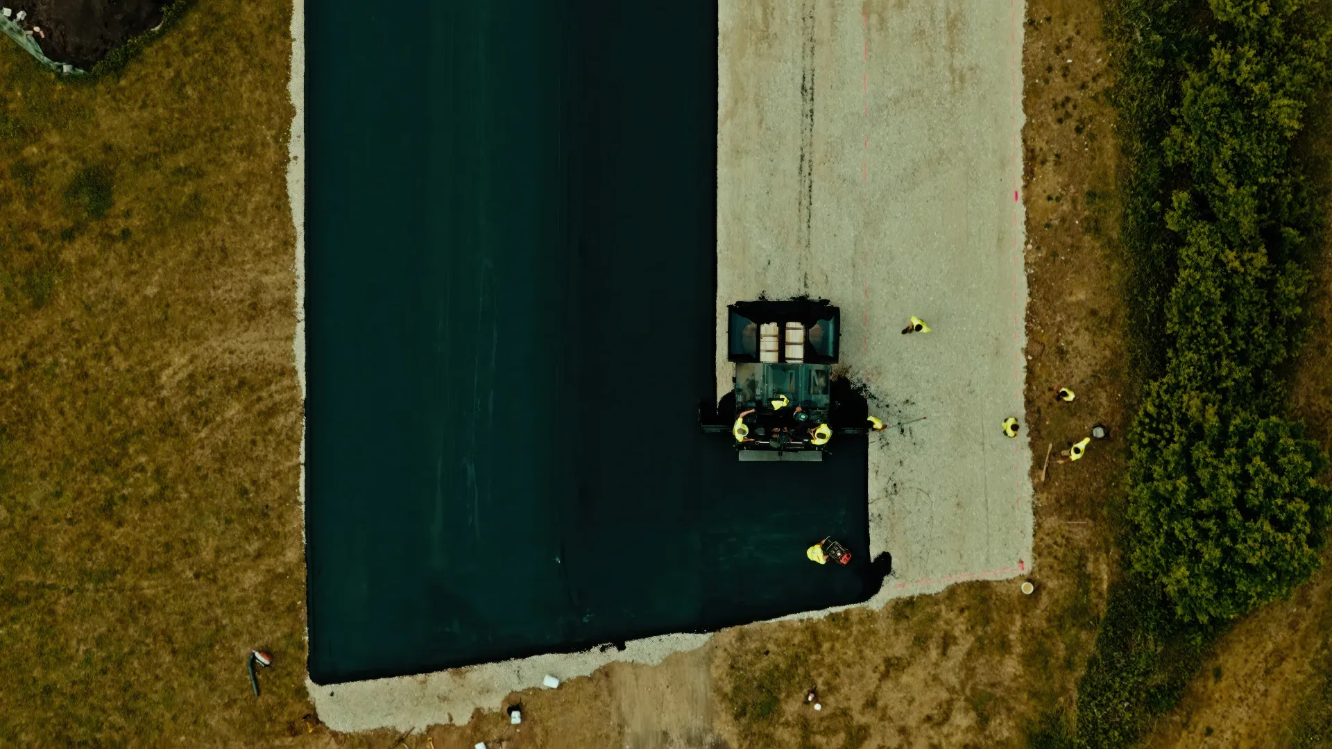 Aerial view of a small boat docked beside a concrete pier and dark green water