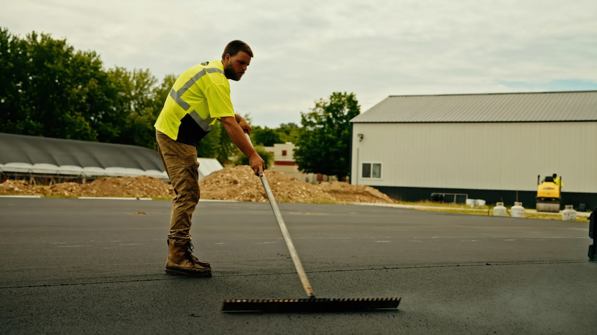Road crew operating an asphalt paver beside a dump truck during a paving project.