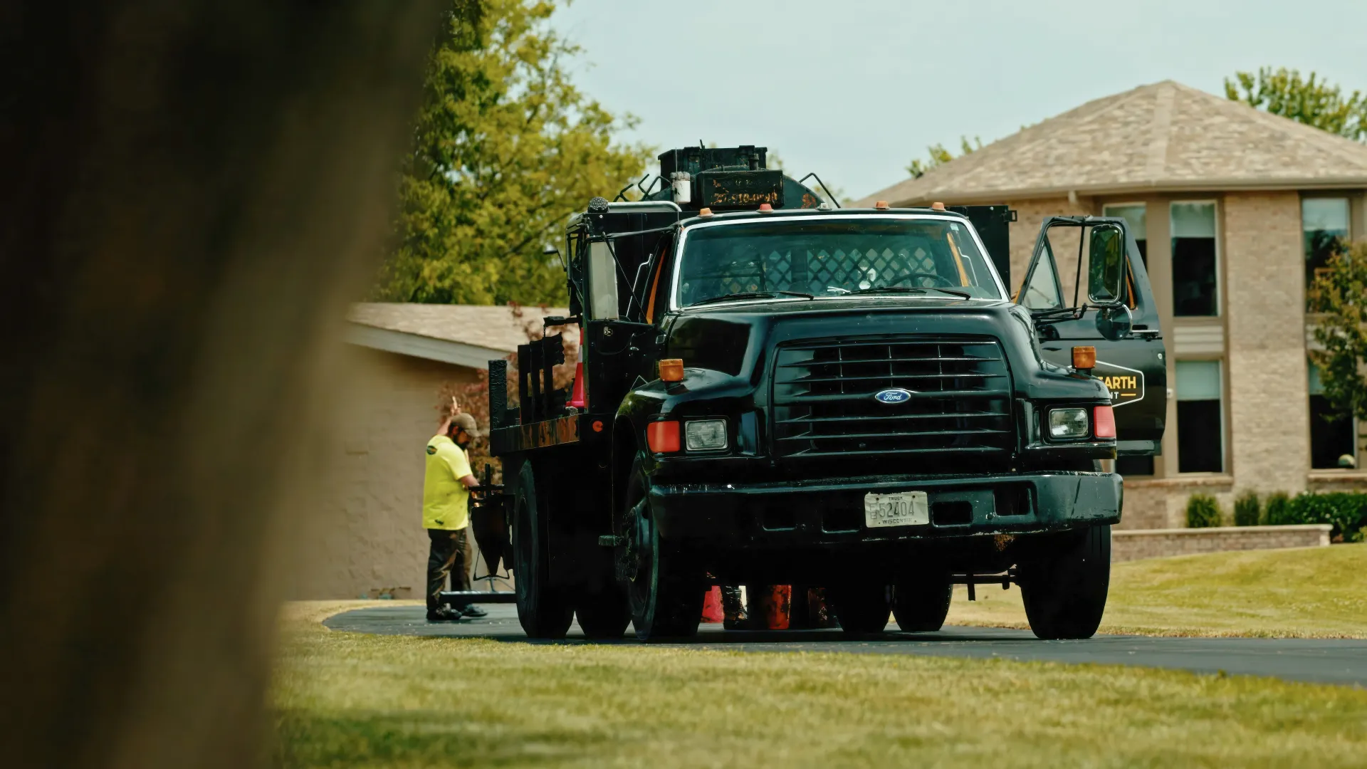 Road crew operating an asphalt paver beside a truck during a paving project.