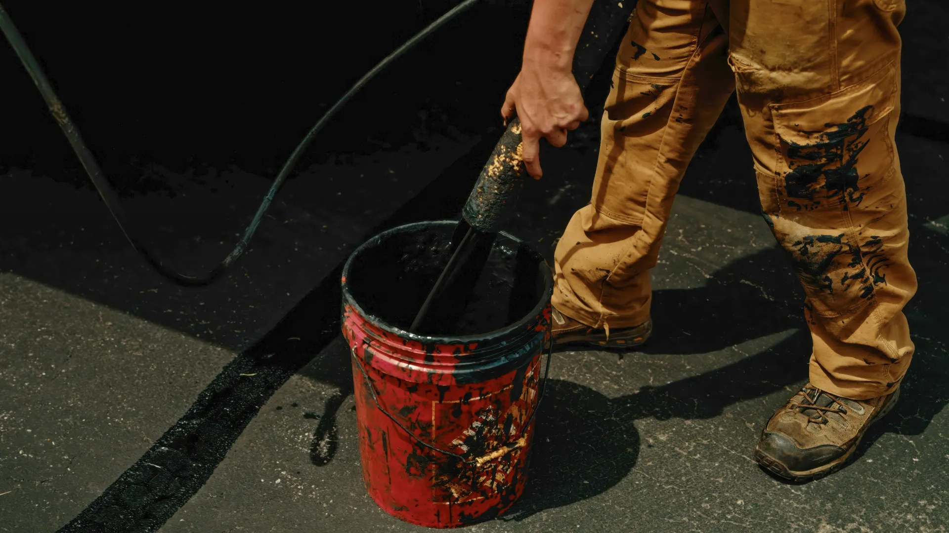 Road crew operating an asphalt paver beside a dump truck during a paving project.