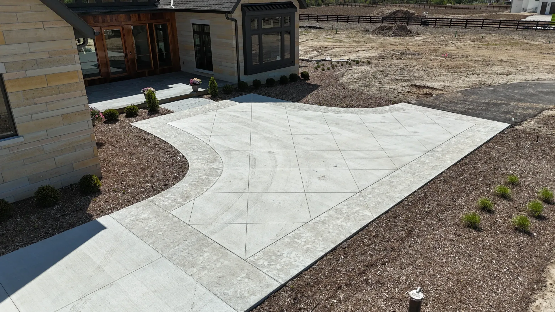 Concrete walkway leading to a house entrance, bordered by mulch and desert landscaping.