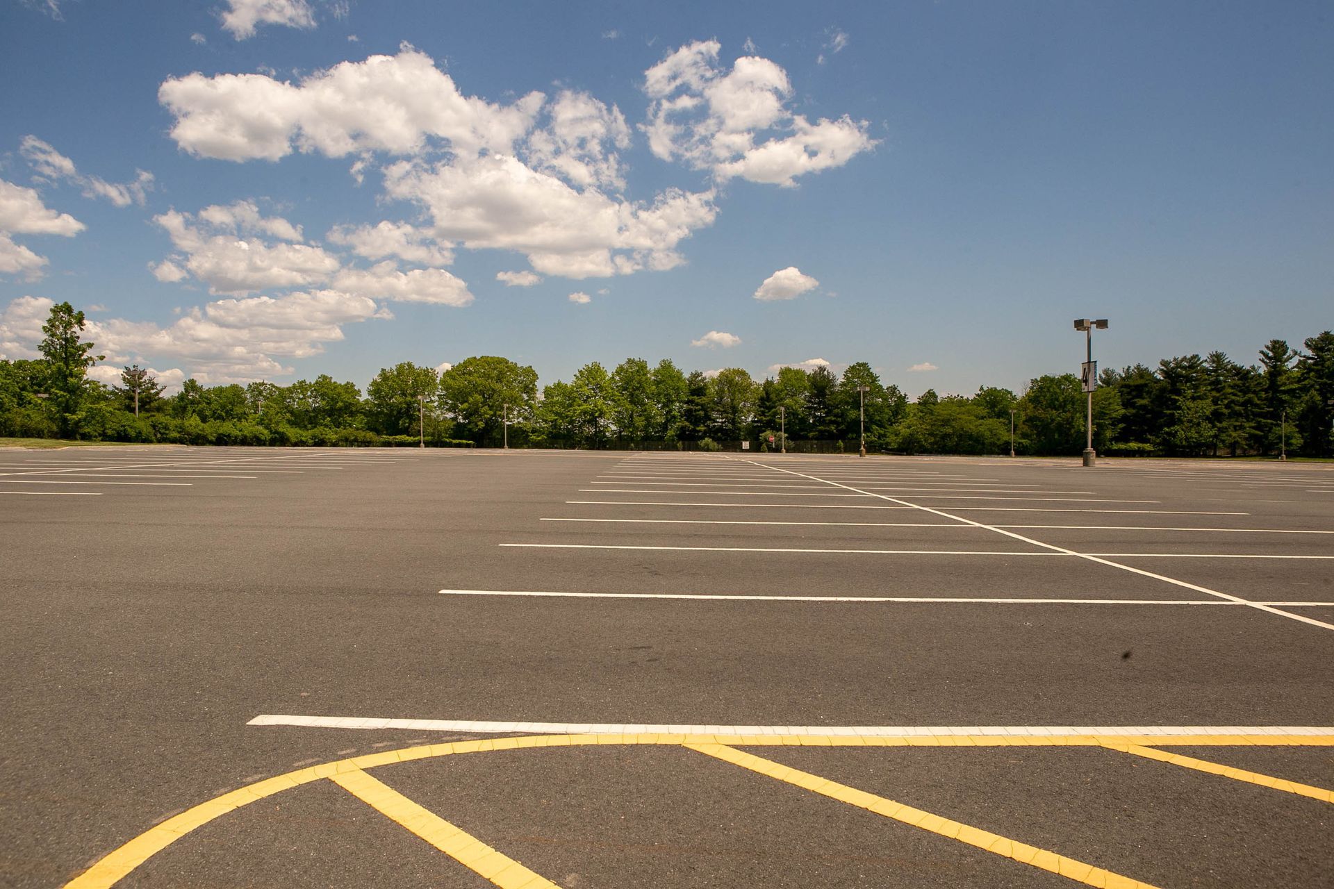 Empty parking lot with yellow markings under a blue sky and clouds