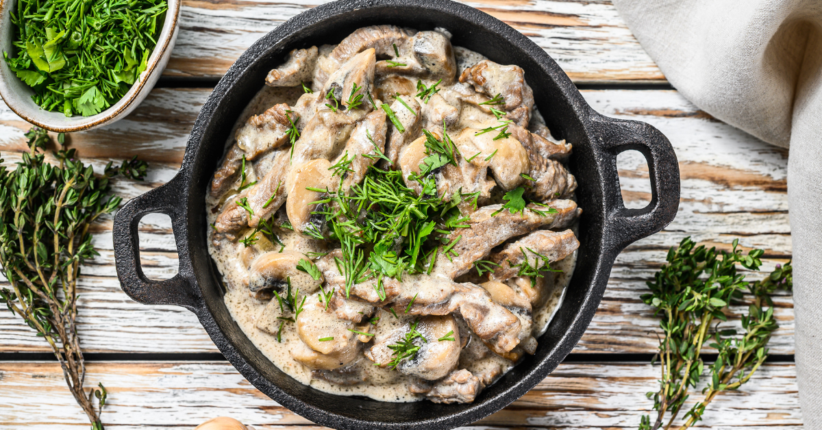A pan filled with mushrooms and sauce on a wooden table.