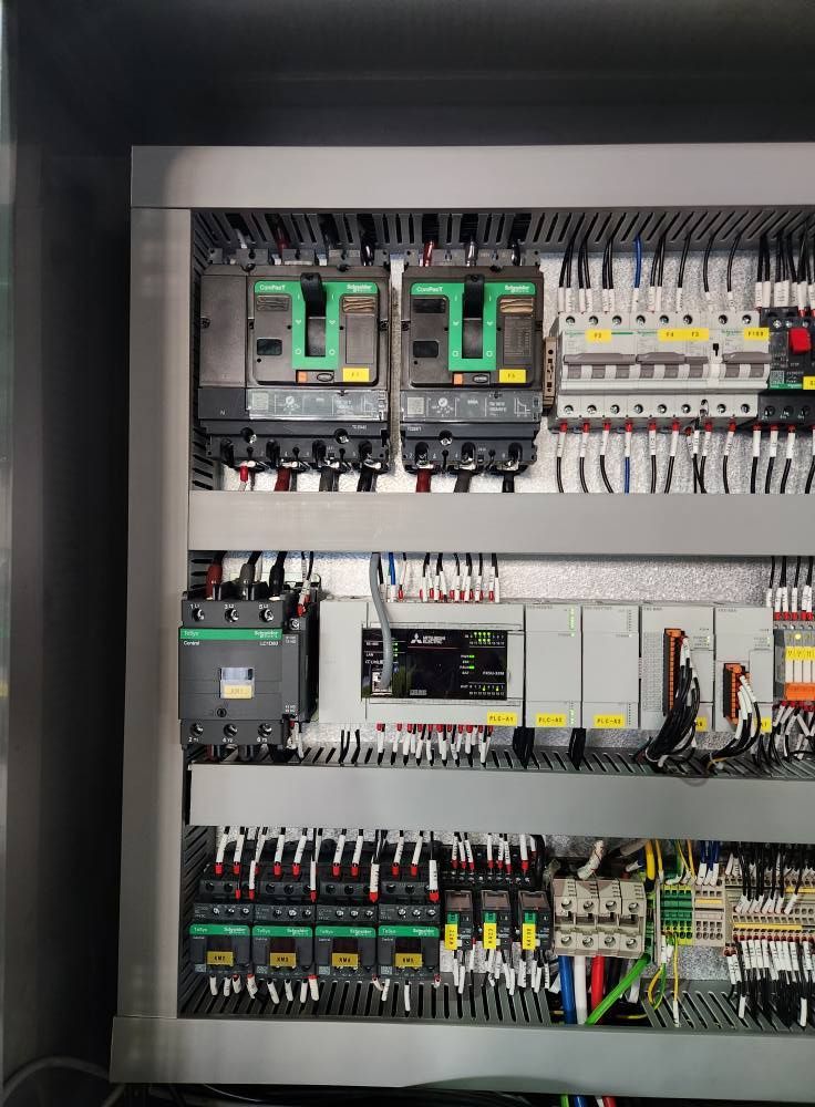 Open electrical control panel with breakers, relays, wiring, and terminal blocks.