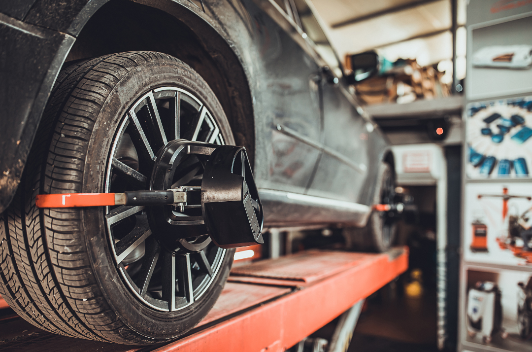 A car is being adjusted on a lift in a garage.