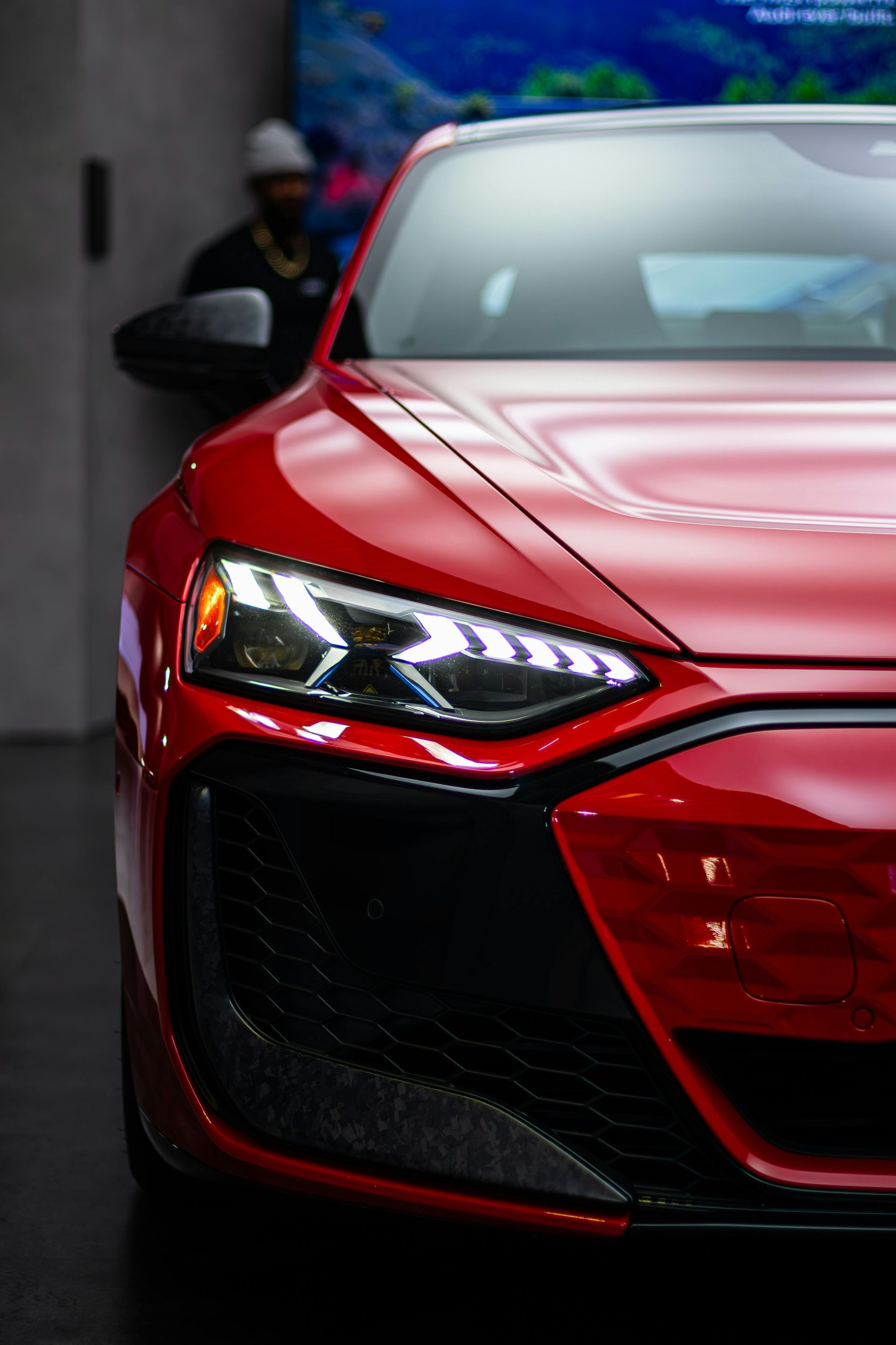 Red sports car front end with sleek headlights in a dim garage