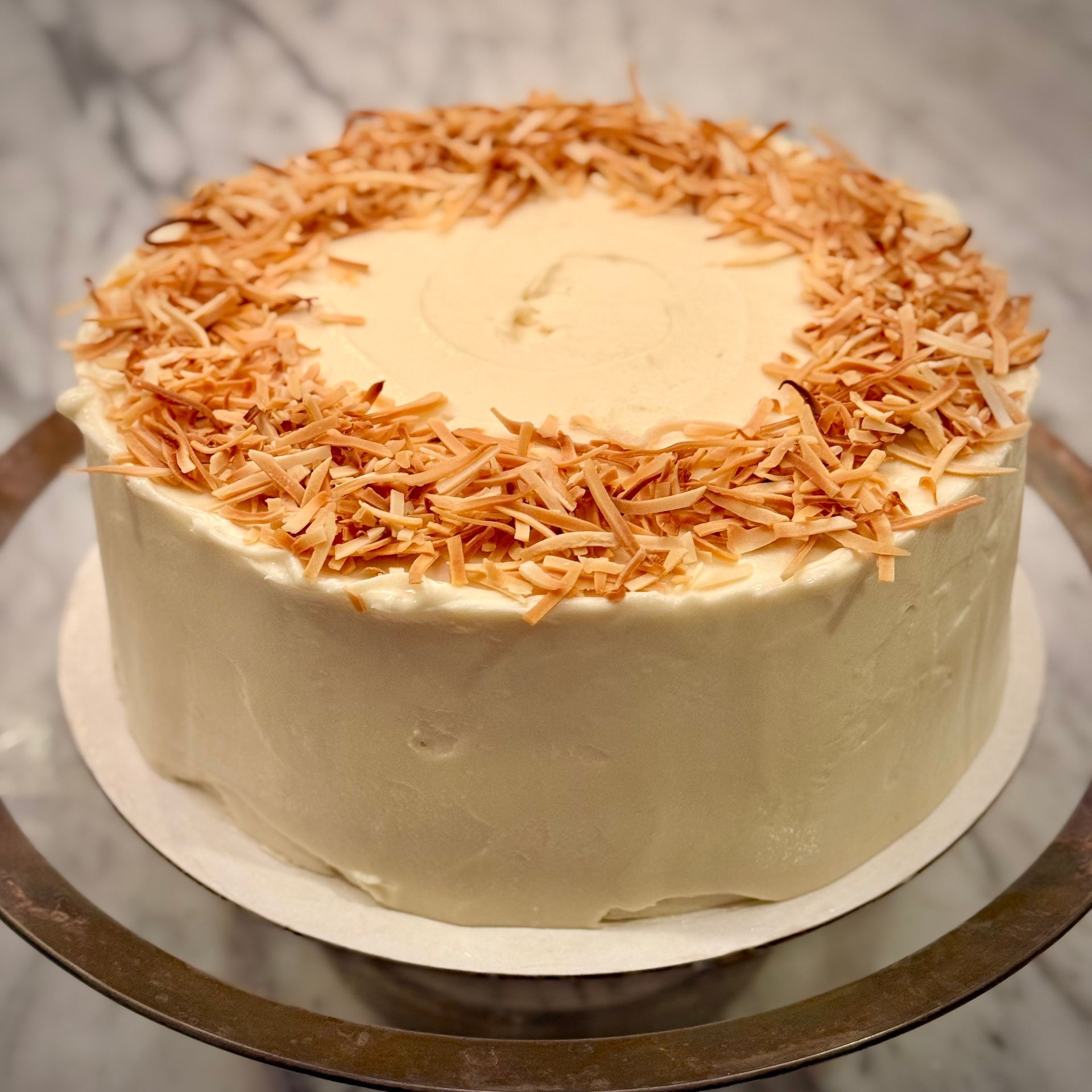 Coconut cake with cream frosting and toasted coconut garnish