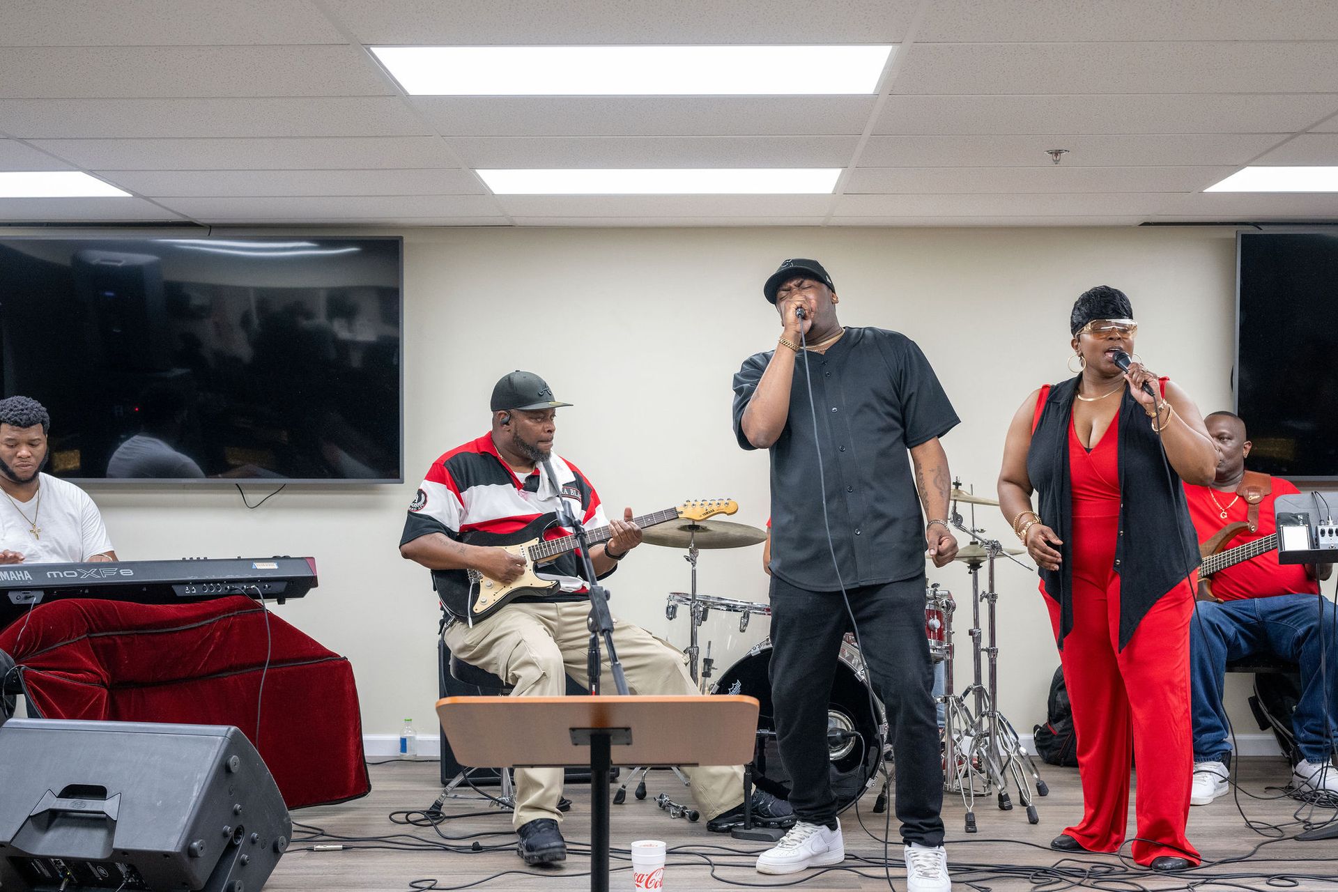 A group of people are standing on a stage playing instruments and singing into microphones.
