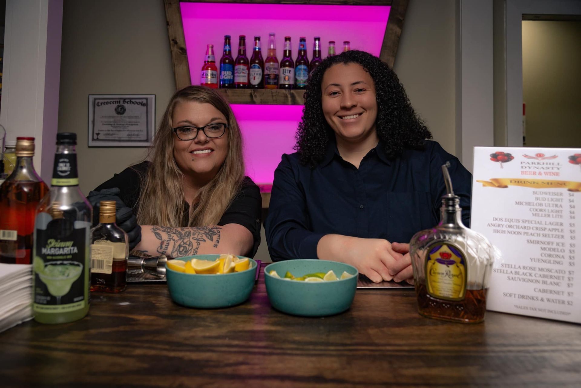Two women are standing next to each other at a bar.