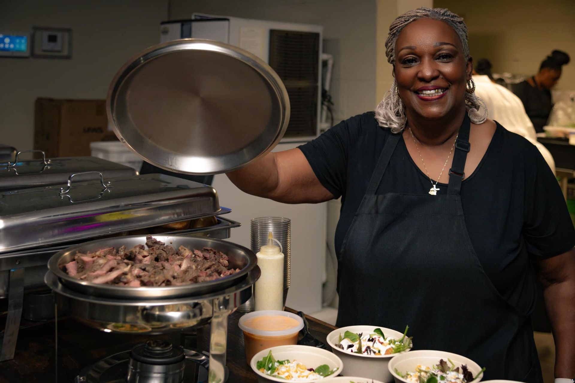 A woman is standing in front of a buffet table with plates of food.