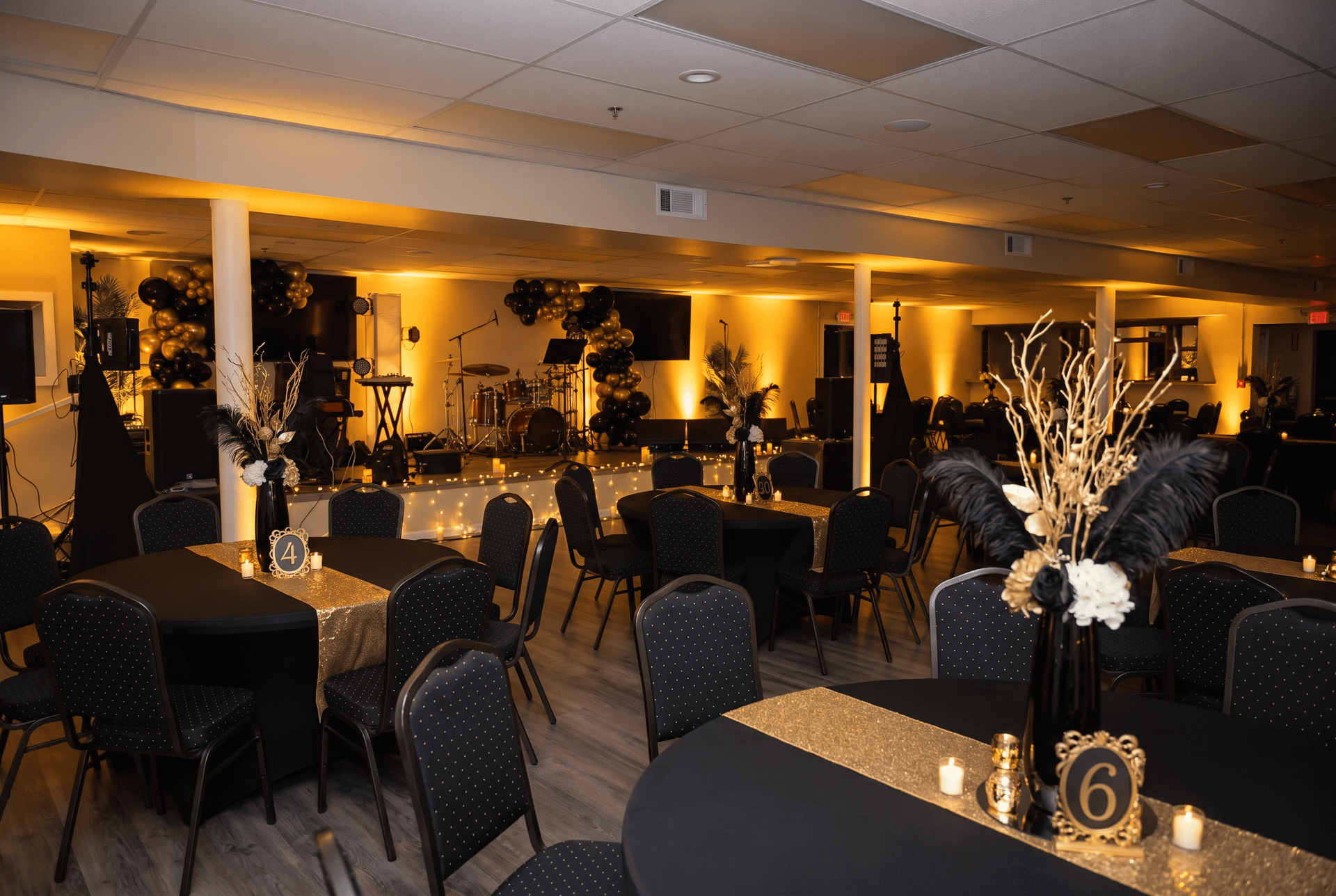 Warmly lit banquet hall with black tablecloths and round tables