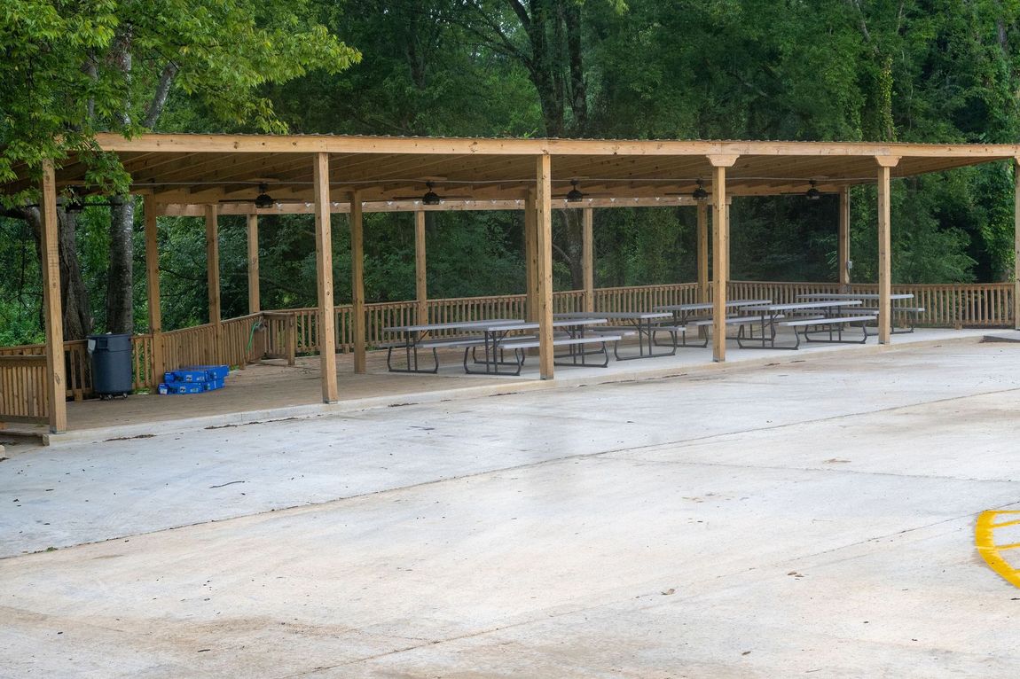A row of wooden picnic tables under a covered area