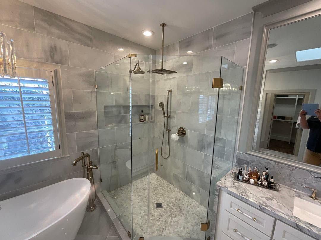 Modern bathroom with glass shower, freestanding tub, marble vanity, and large mirror