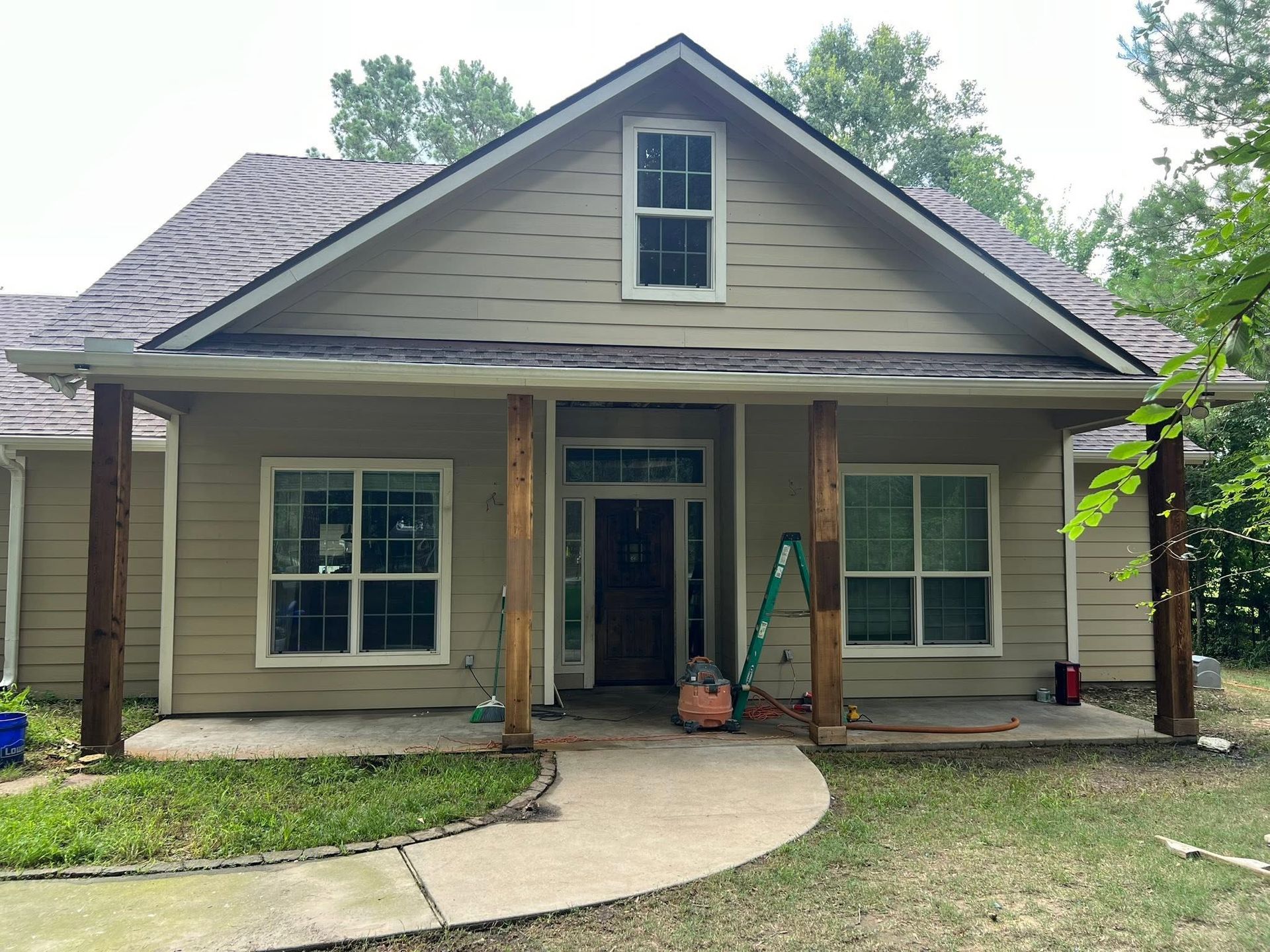 Front view of a tan house with a curved concrete walkway and covered porch