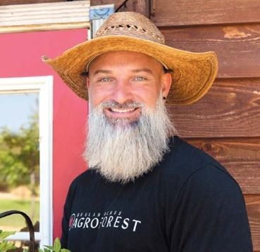 A man with a beard wearing a cowboy hat and a shirt that says agroforest