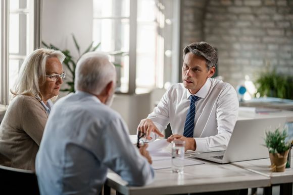 A man and a woman are sitting at a table talking to each other.