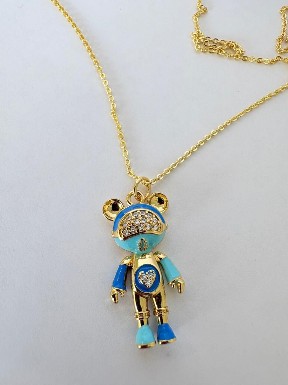 Collar dorado con un colgante de osito de peluche de colores sobre un fondo blanco