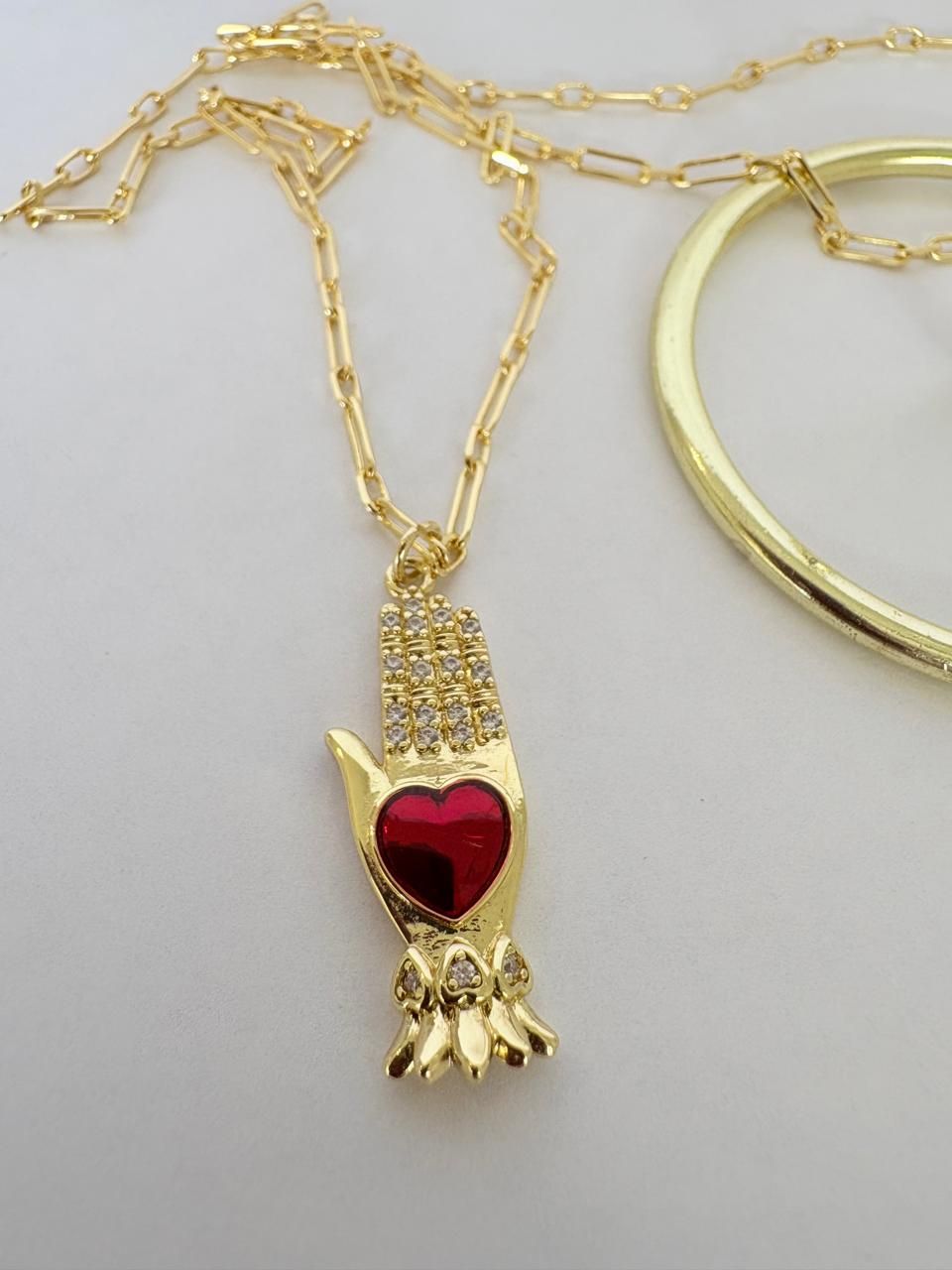 Collar de oro y colgante expuestos en un soporte sobre un fondo claro