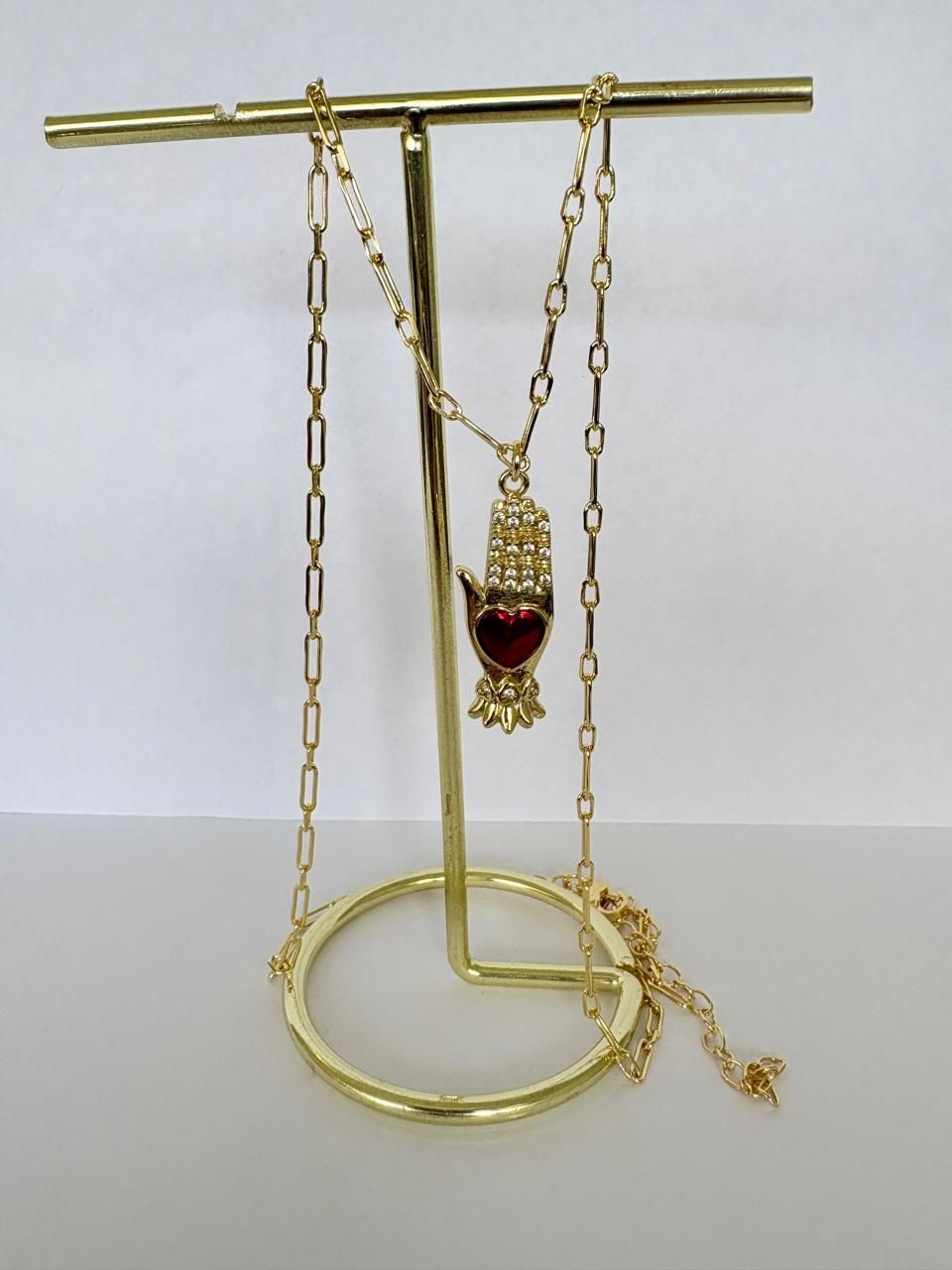 Collar de oro y colgante expuestos en un soporte sobre un fondo claro