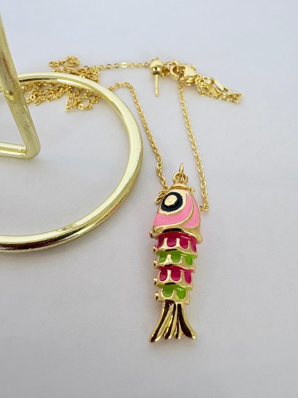 Colgante dorado con forma de pez, con esmalte turquesa y azul oscuro, en una cadena