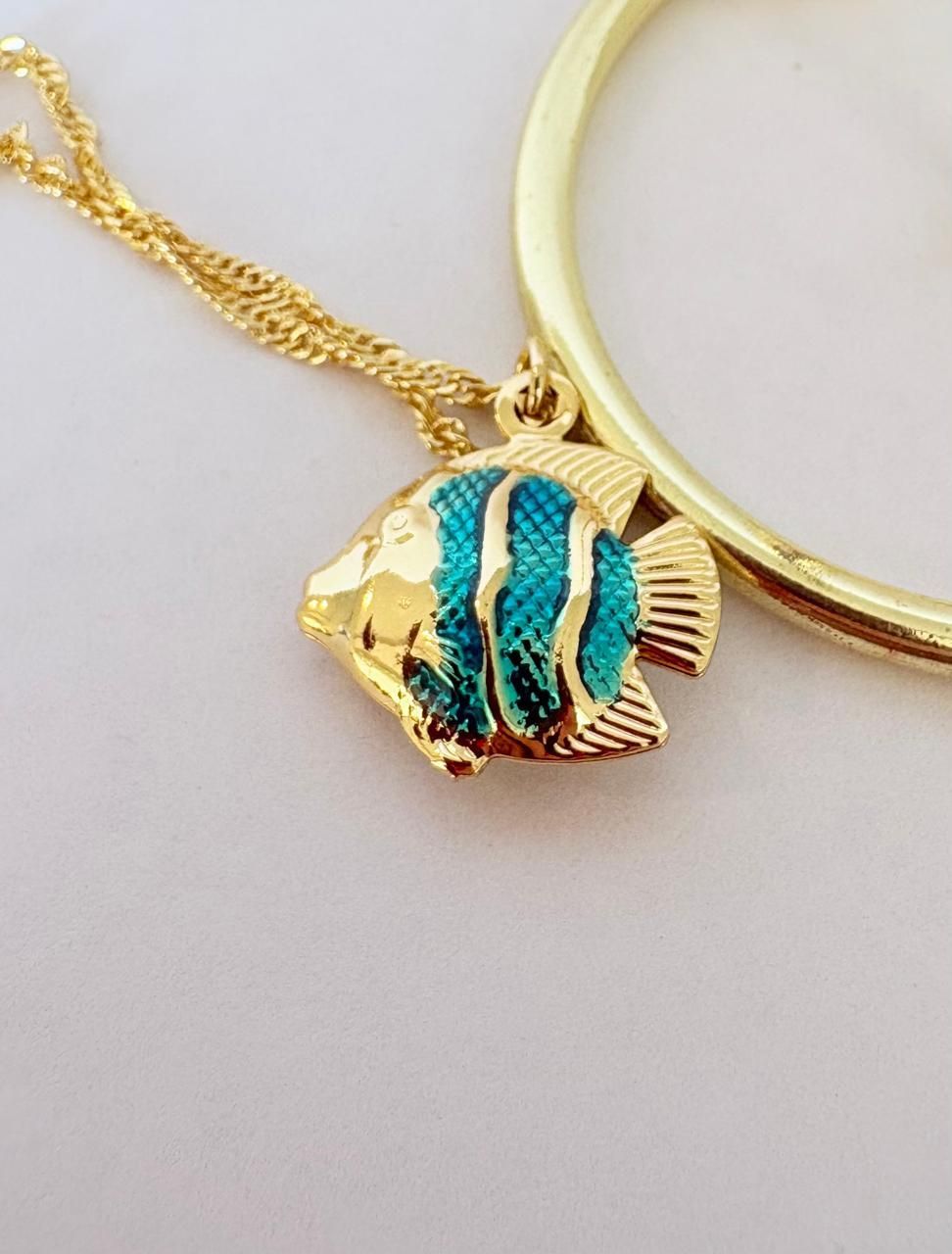 Expositor dorado para joyas con dos collares de colgantes de peces de colores y una pulsera a juego en exhibición