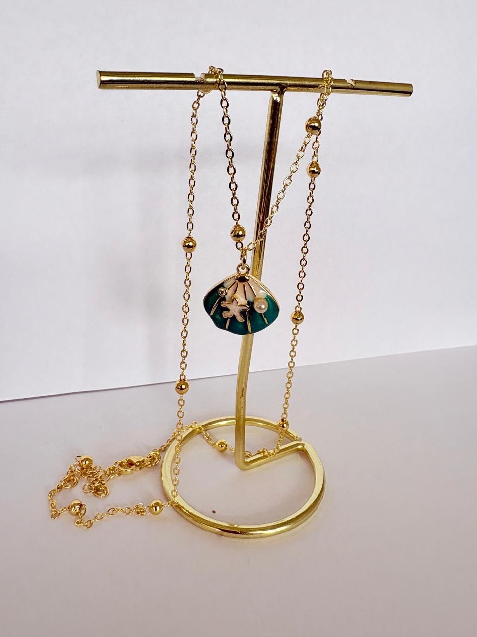 Collar de oro con un colgante de tortuga verde sobre un fondo claro