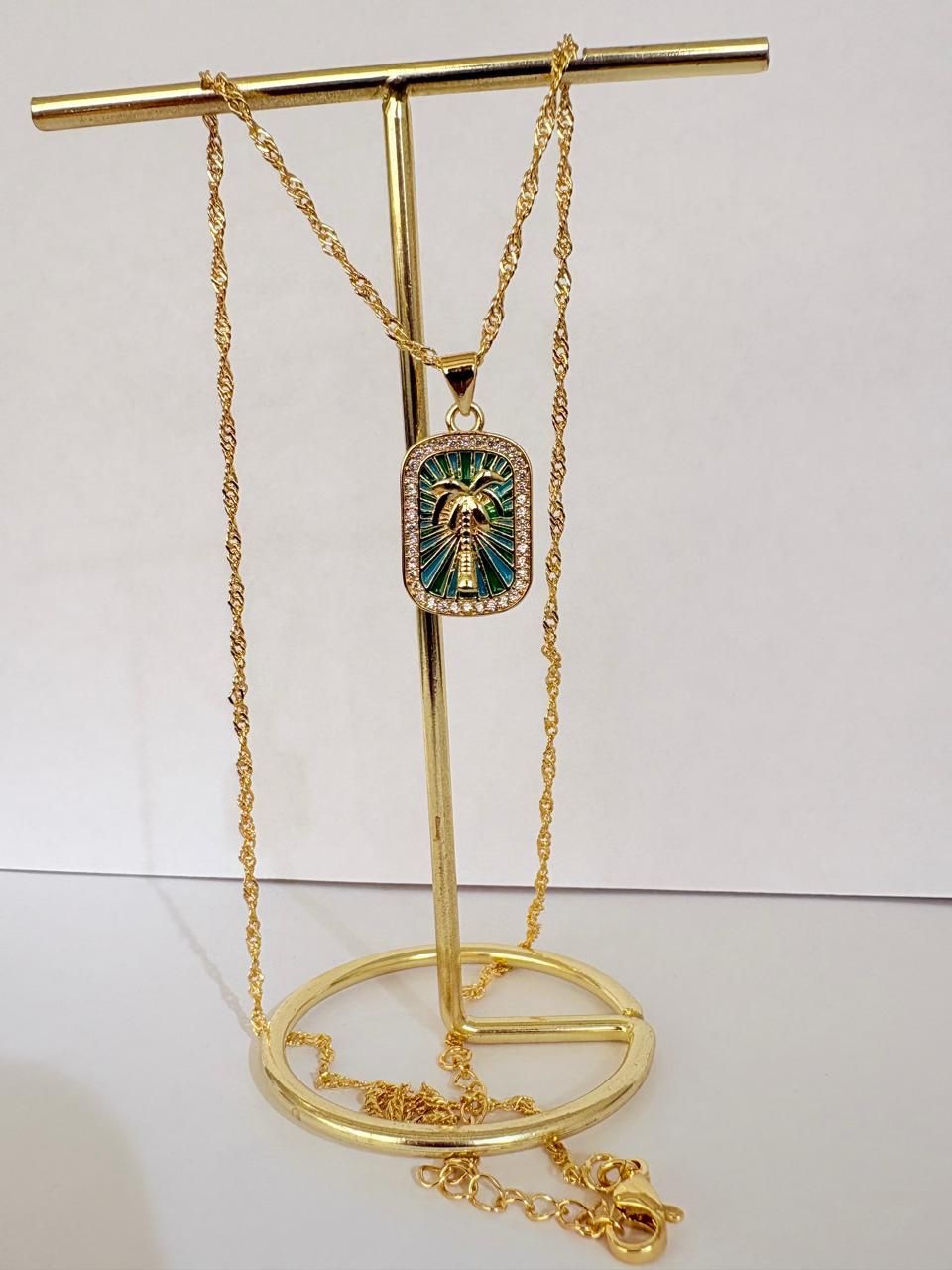Colgante de cadena de oro colgado de un soporte dorado, con un adorno decorativo rojo y blanco.