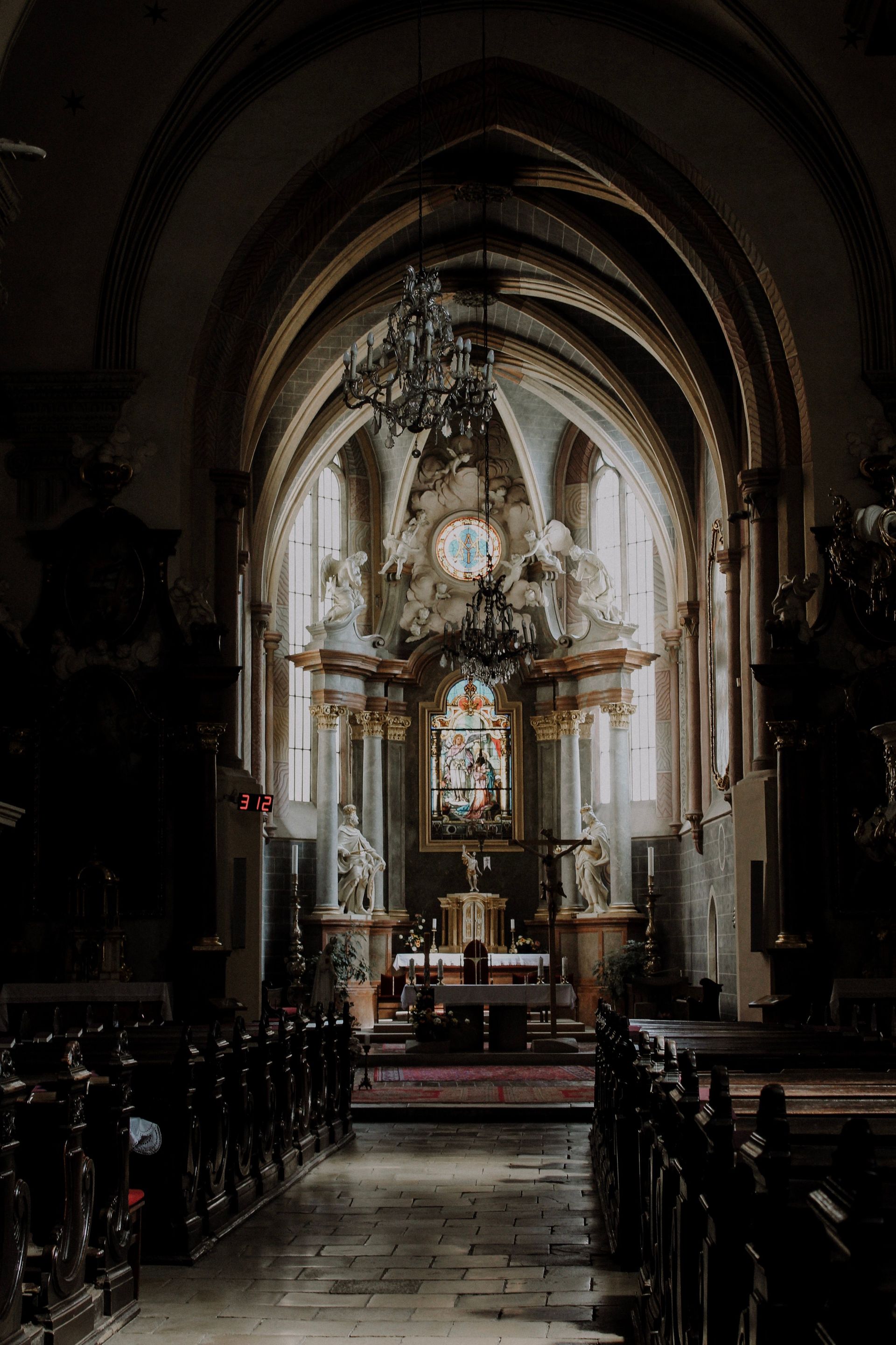 Woman looking up in a church, wearing a patterned scarf, with a dark interior.