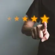 Hand pointing at a row of glowing star ratings on a dark background